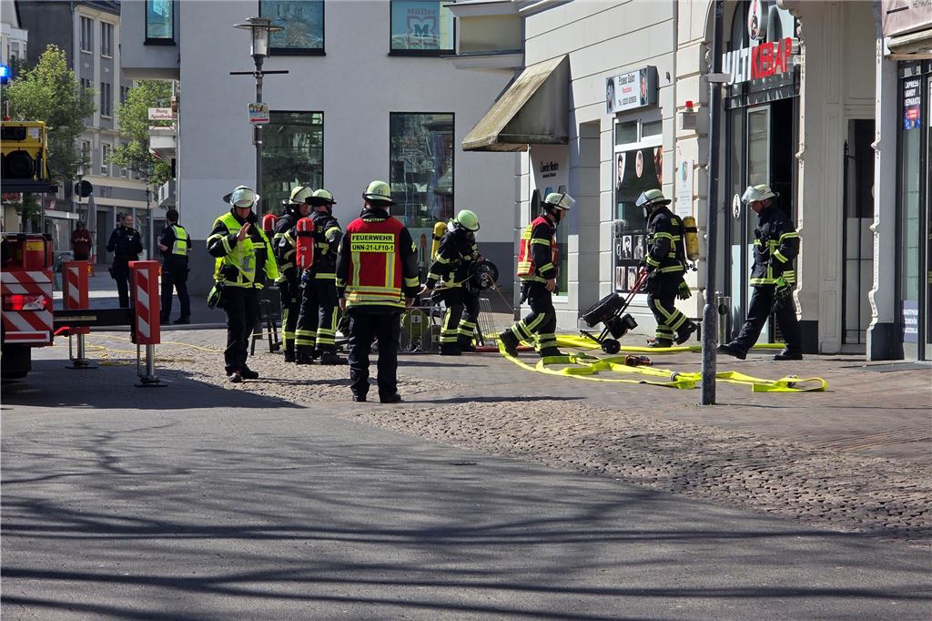 Einsatzkräfte der Feuerwehr stehen vor Imbiss in Bahnhofstraße in Unna