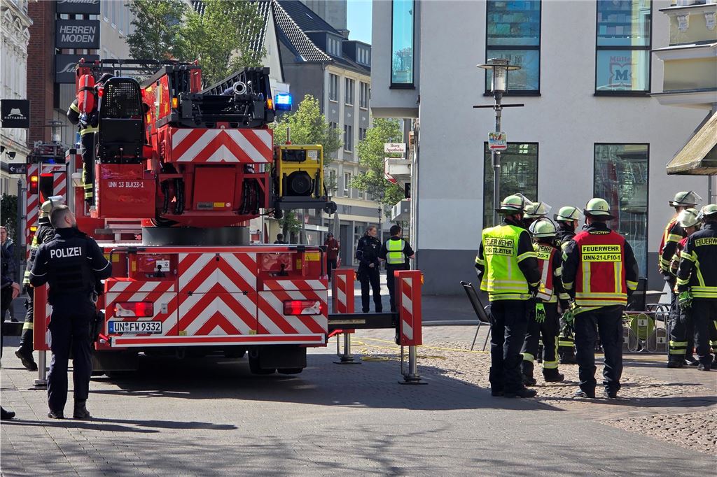 Einsatzkräfte der Feuerwehr stehen vor Imbiss in Bahnhofstraße in Unna