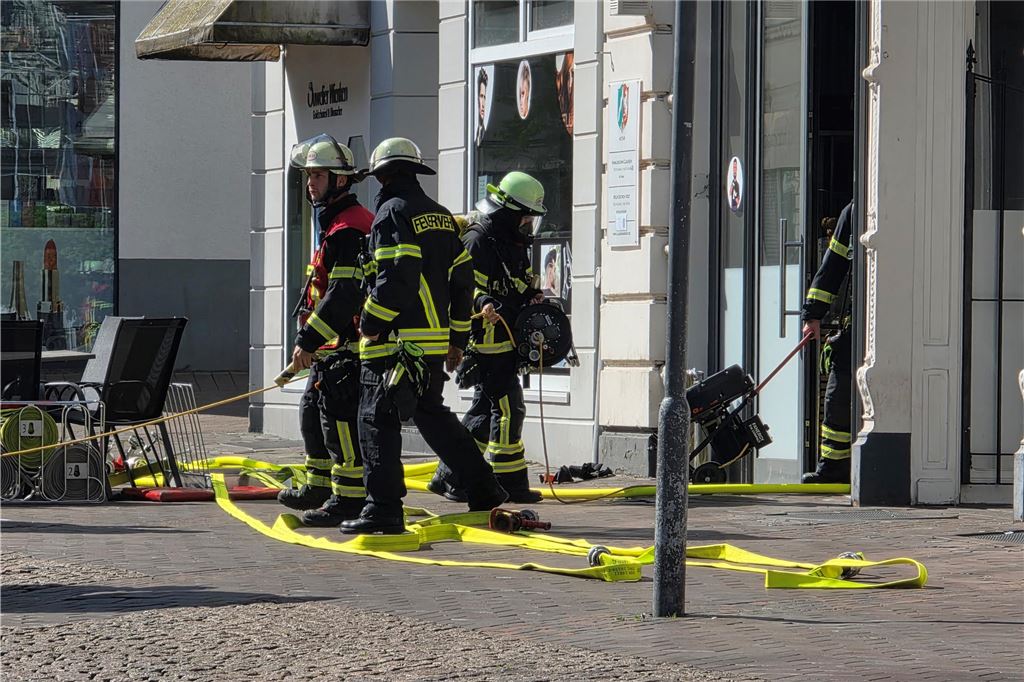 Einsatzkräfte der Feuerwehr stehen vor Imbiss in Bahnhofstraße in Unna