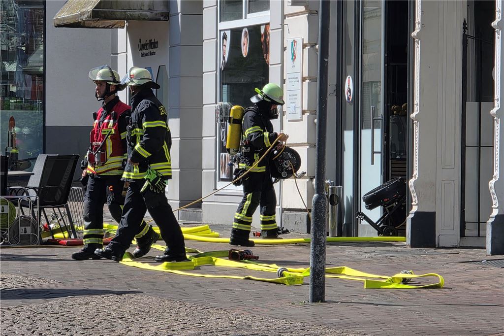 Einsatzkräfte der Feuerwehr stehen vor Imbiss in Bahnhofstraße in Unna