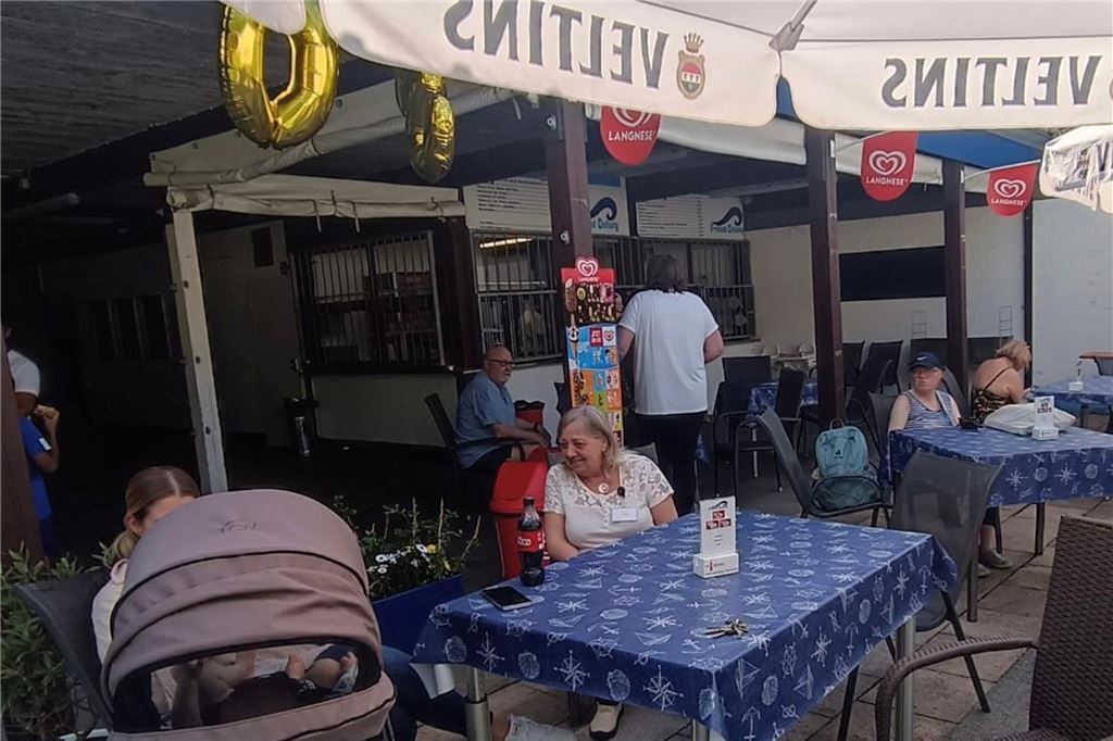 Fröndenberger strömen ins Freibad Dellwig: Das zeigt Verbundenheit Menschen sitzen vor dem Kiosk im Freibad.