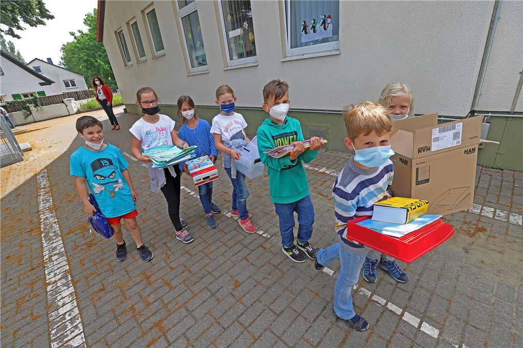 Offene Ganztagsschule: Halbzeit bei der Ausbauplanung Eine Gruppe von Grundschulkindern trägt in Umzugskartons und Kisten Unterrichtsmaterial über den Schulhof.