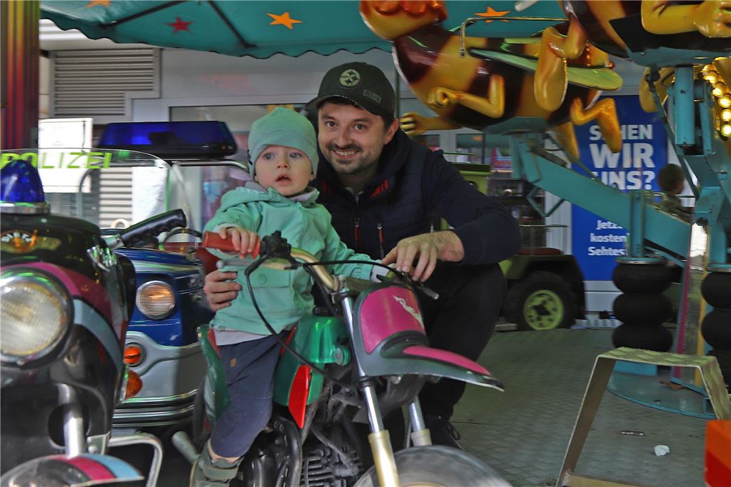 Ein Papa hält sein Kind im Karussell fest.