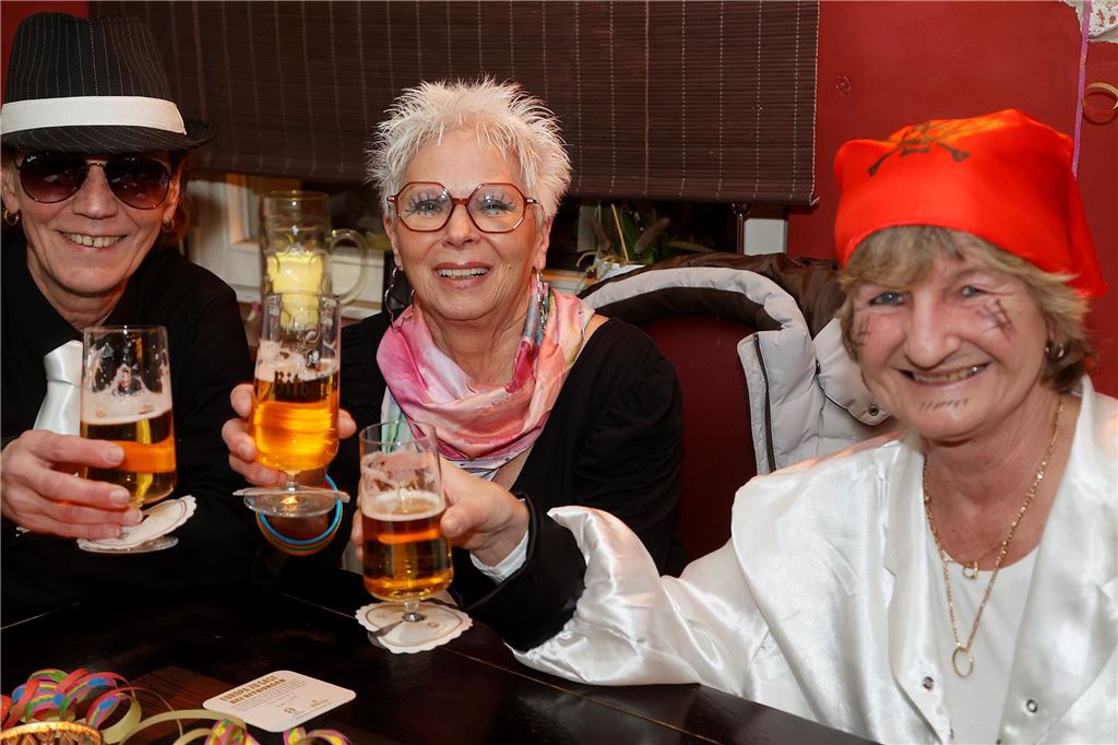 Drei Frauen prosten sich mit ihren Bieren zu.