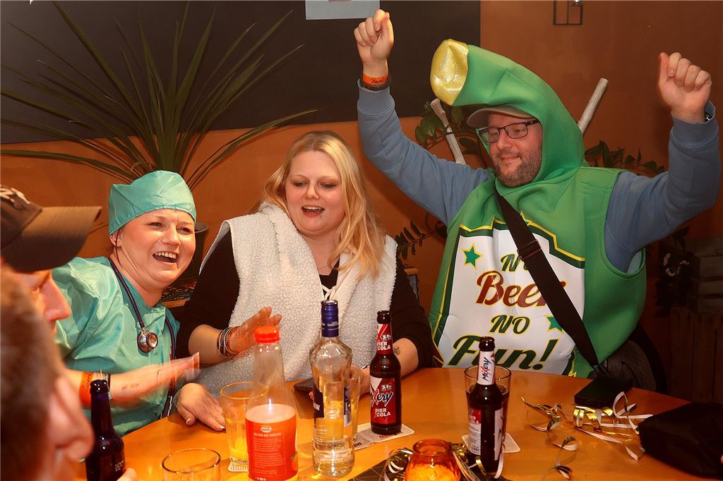 Eine "Krankenschwester" und eine Bierflasche sitzen am Tisch. Die Bierflasche jubelt.