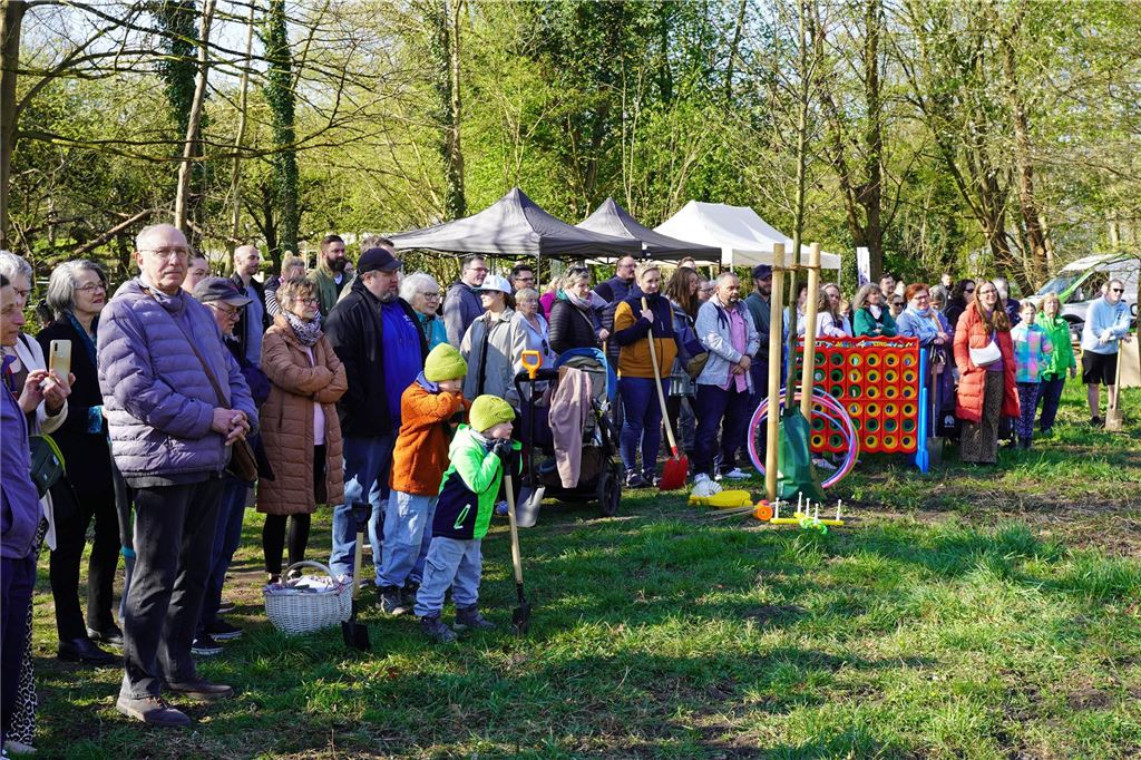 Start des Bürgerwalds: Unnaer pflanzen 40 neue Bäume im Kurpark Viele Menschen, einige mit Schaufeln, stehen an einer Wiese im Kurpark in Unna