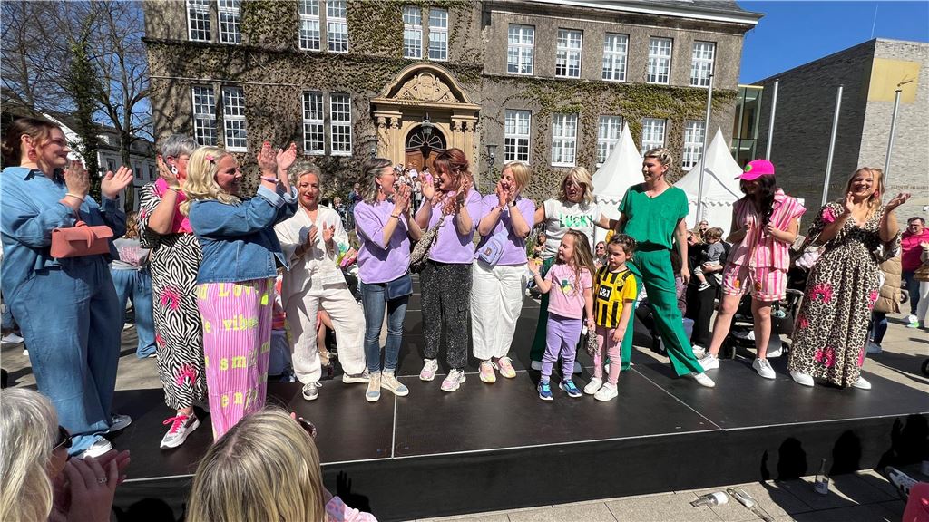 Modenschau von DekoRieger: „Es ist einfach eine Bombenstimmung“ Mehrere Menschen stehen auf dem Laufsteg der Modenschau auf dem Holzwickeder Marktplatz.