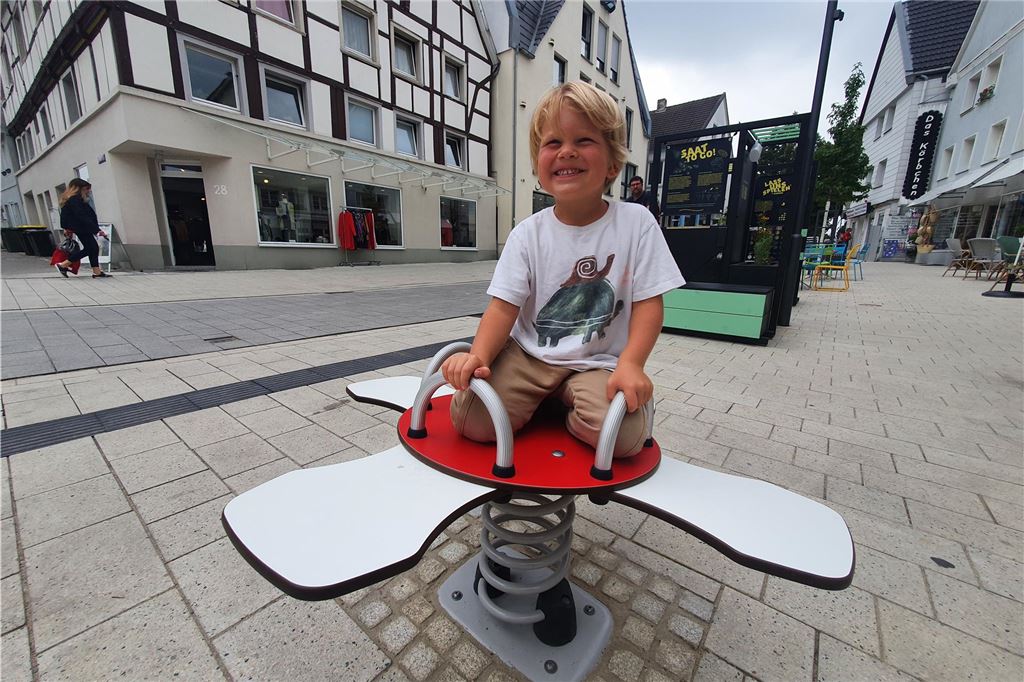 Neubaupläne für die Bahnhofstraße Ein fröhlich lächelndes Kind spielt auf einem Wippgerät an der Massener Straße.