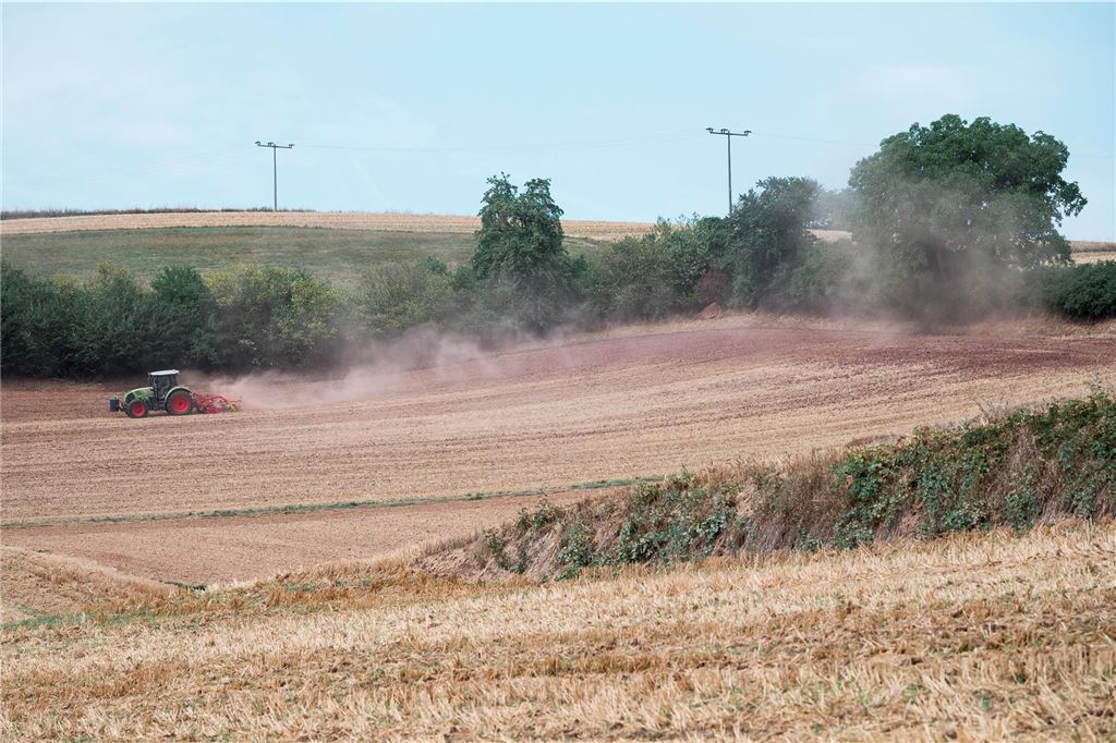 Auswirkungen der Klimakrise auf NRW: Hitze, Flut und gesundheitliche Folgen Trockene Felder an einem Hügel. Ein Traktor pflügt ein Feld.
