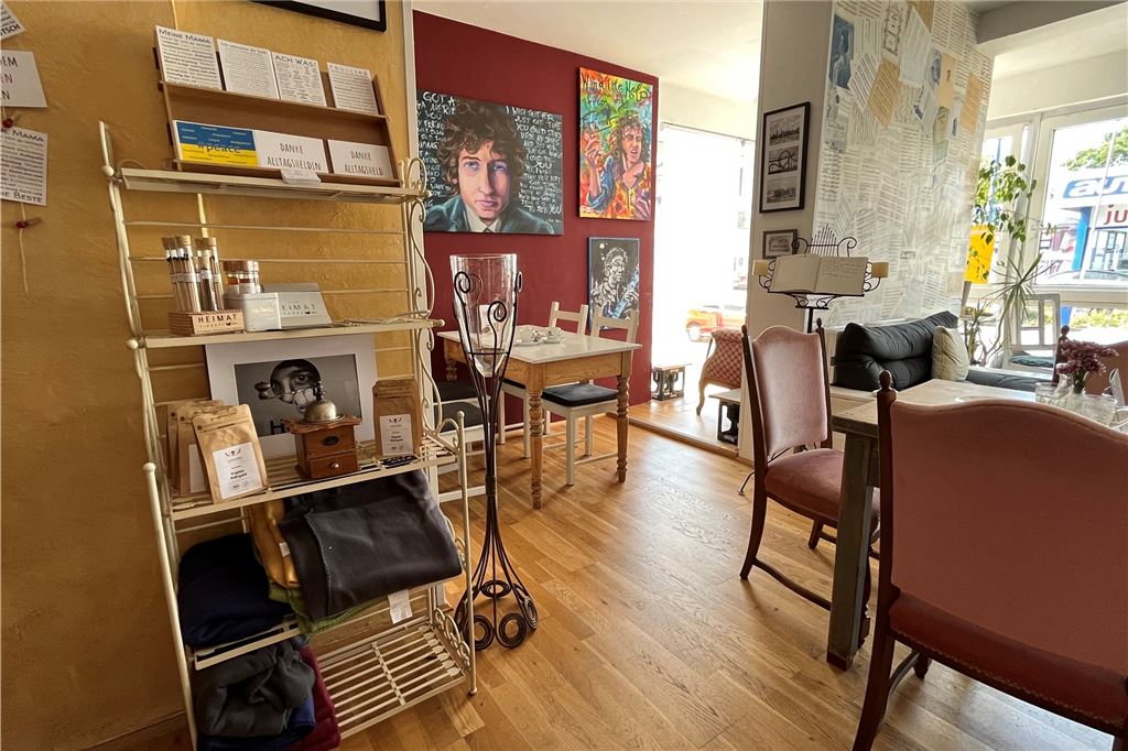 Café Note: Inhaber Christoph Wiesweg steht vor neuen Herausforderungen Bereich des Cafés, in dem hinten Gemälde mit Musikern hängen, Tische und Stühle im Vordergrund und ein Regal mit Kaffeemühle, Bohnen und Postkarten.