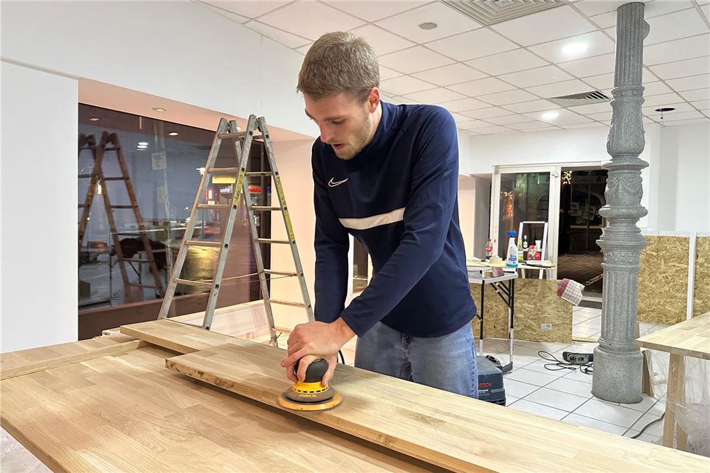 SPD zieht in Ladenlokal in der Innenstadt: „Ort der Begegnung“ Ein Mann schleift ein Holzbrett.