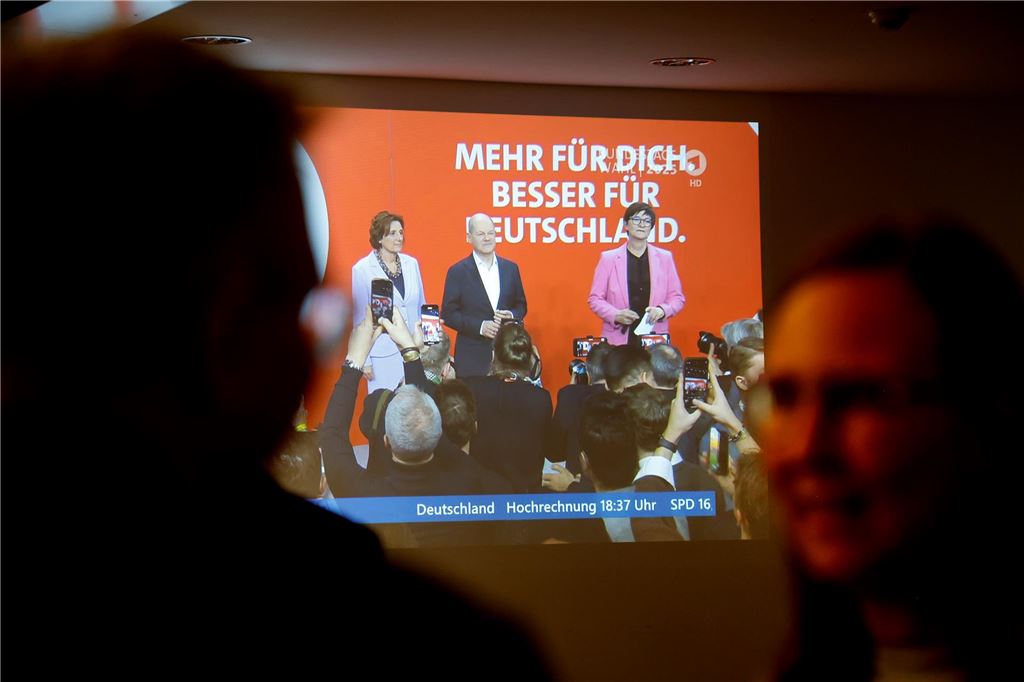 Kreis-AfD zieht gemischte Bundestagswahl-Bilanz Besucher der Wahlparty im Kreishaus Unna stehen am Sonntag (23. Februar 2025) vor einer Leinwand, auf der eine TV-Übertragung einer SPD-Wahlveranstaltung mit Bundeskanzler Olaf Scholz läuft.