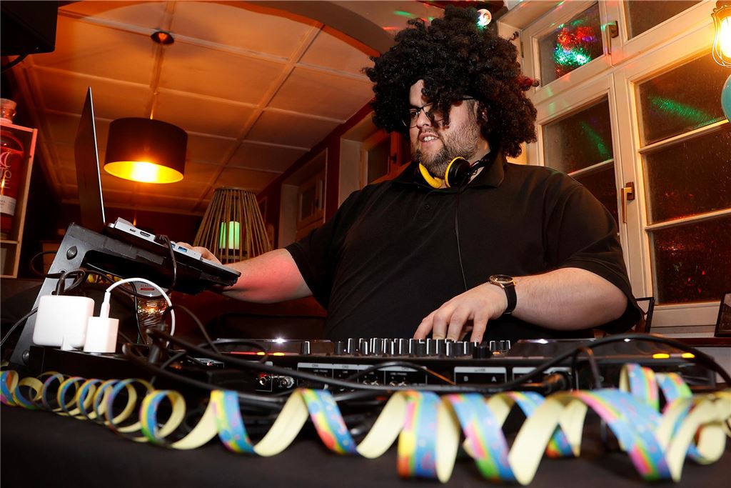 Ein DJ mit Perücke hinterm DJ-Pult.