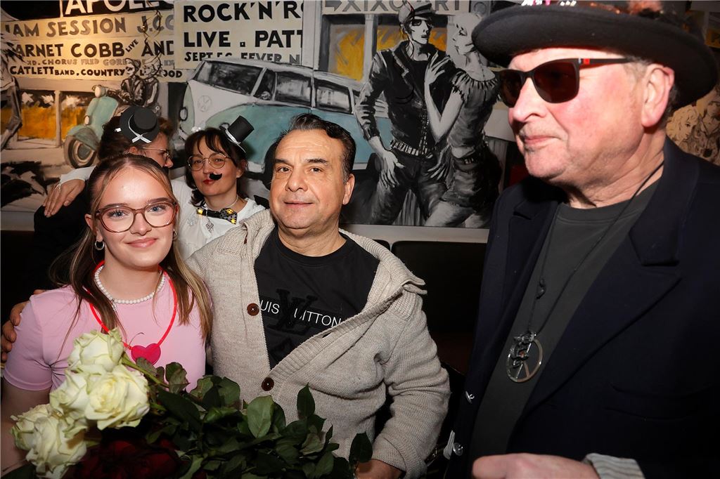 Zwei Männer und eine Frau, Rosen im Vordergrund.