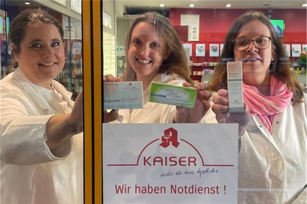 Was erleben Apotheker im Notdienst? Vom Fieberzäpfchen bis zum Notfall Dr. Stephanie Begrow, Jennifer Obornik und Marion Schwalk (von links nach rechts) stehen den Patienten im Notdienst zur Verfügung. Sie stehen hinter einer Scheibe und halten Medikamente fest.
