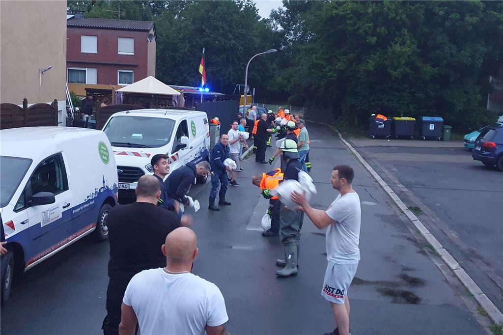 Hochwasser hält Unna-Massen bis in die Nacht in Atem In Obermassen bildeten Anwohner und Rettungskräfte für den Sandsacktransport eine Menschenkette in der Straße Im Kamp.