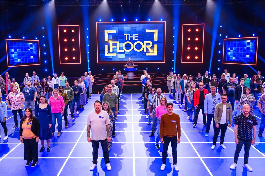 Zweite Staffel von „The Floor“: Drei Dortmunder kämpfen um Quiz-Krone Die 100 Quizzer stehen aufgereiht in ihren Quadraten für ein Foto bereit. im Hintergrund ist in goldener Schrift auf blauem Untergrund "The Floor" zu lesen.