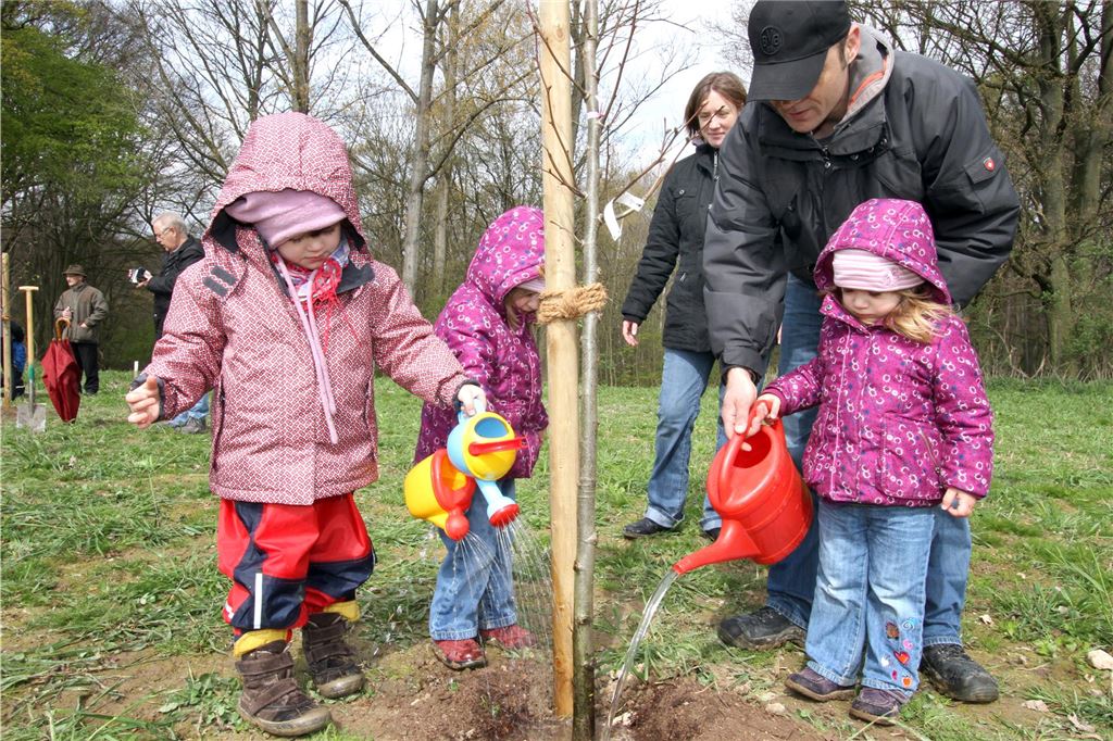 Neuer Bürgerwald: Unnaer sollen Bäume stiften für Geburten und Jubiläen Gemeinsam mit zwei Erwachsenen gießen kleine Kinder einen jungen Baum