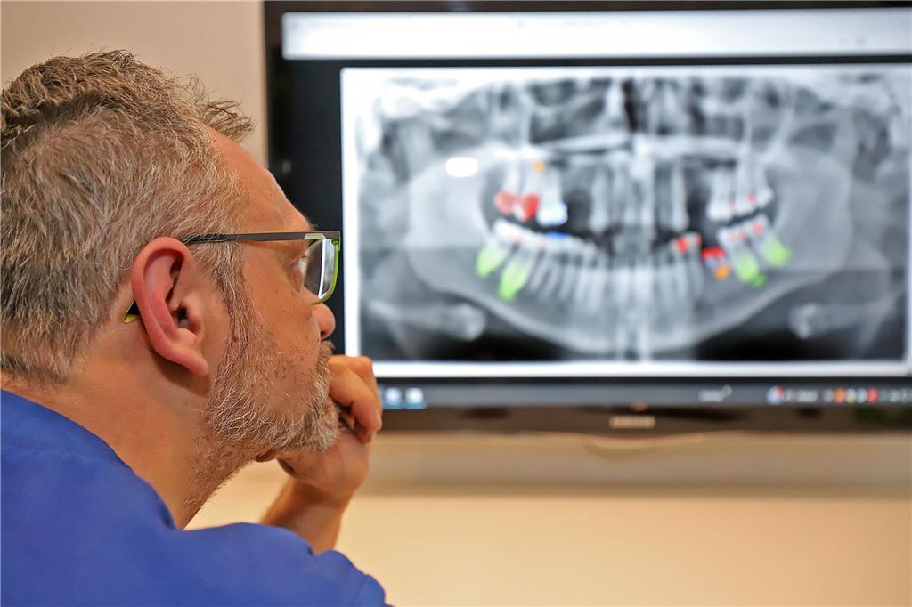 Dentalzentrum wird 50 Jahre alt: Künstliche Intelligenz verändert die Arbeit Zahnarzt Sebastian Spellmeyer aus Unna schaut auf ein Röntgenbild, auf dem mithilfe von KI Erkrankungen zu erkennen sind.