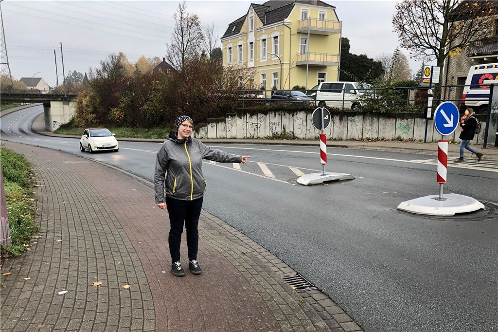 Mehr 30 auf Straßen, dafür Tempo an Unnas Bahnhöfen An der Massener Bahnhofstraße in Unna steht eine Frau. Sie zeigt auf eine Querungshilfe in der MItte der Straße.
