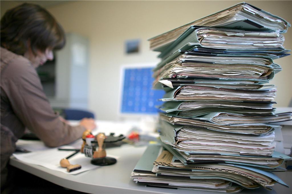 Ausufernde Bürokratie: „Die Unternehmen sind es leid“ Aktenstapel auf einem Schreibtisch.