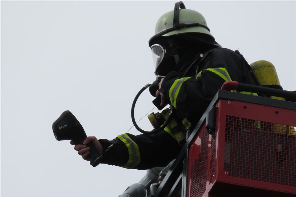 Feuerwehr in der Innenstadt: Brand im Dachstuhl neben Einkaufszentrum Ein Feuerwehrmann steht im Korn einer Drehleiter bei einem Feuerwehreinsatz in Unna.