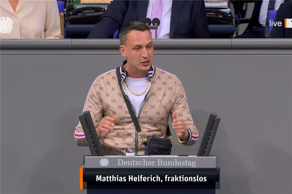 Kubitscheks Schüler: Wie Matthias Helferich zum „freundlichen Gesicht des NS“ wurde Mit Trainingsanzug, Umhängetasche und Goldkette steht Matthias Helferich im Oktober 2024 am Rednerpult des Bundestags.
