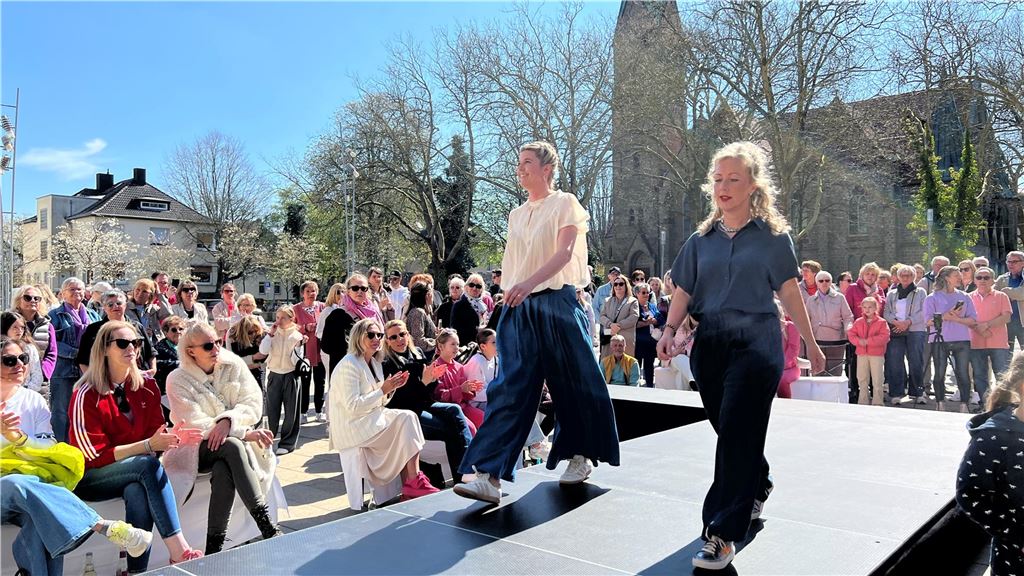 Models präsentieren aktuelle Outfits und Accessoires auf dem Laufsteg mitten auf dem Marktplatz.