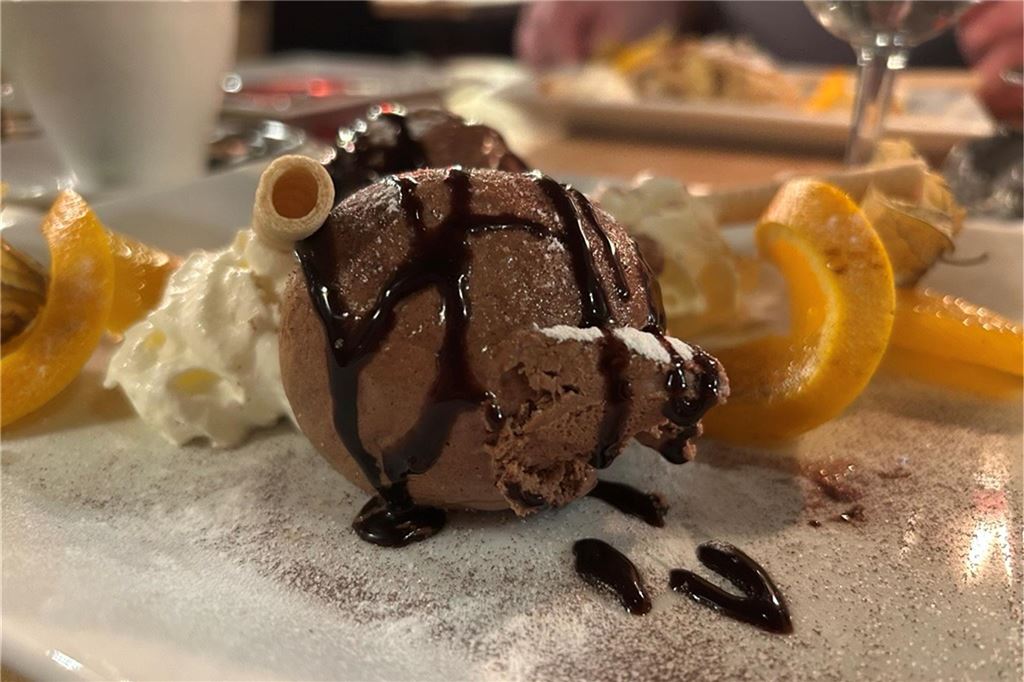 Perfektes Steak und ein Veggie-Experiment im Steakhouse „Le Bon Filet“ Eine Kugel Mousse au Chocolat auf einem weißen Teller mit Schokosauce und Orangenscheiben angerichtet im „Le Bon Filet Steakhouse“ in Dortmund