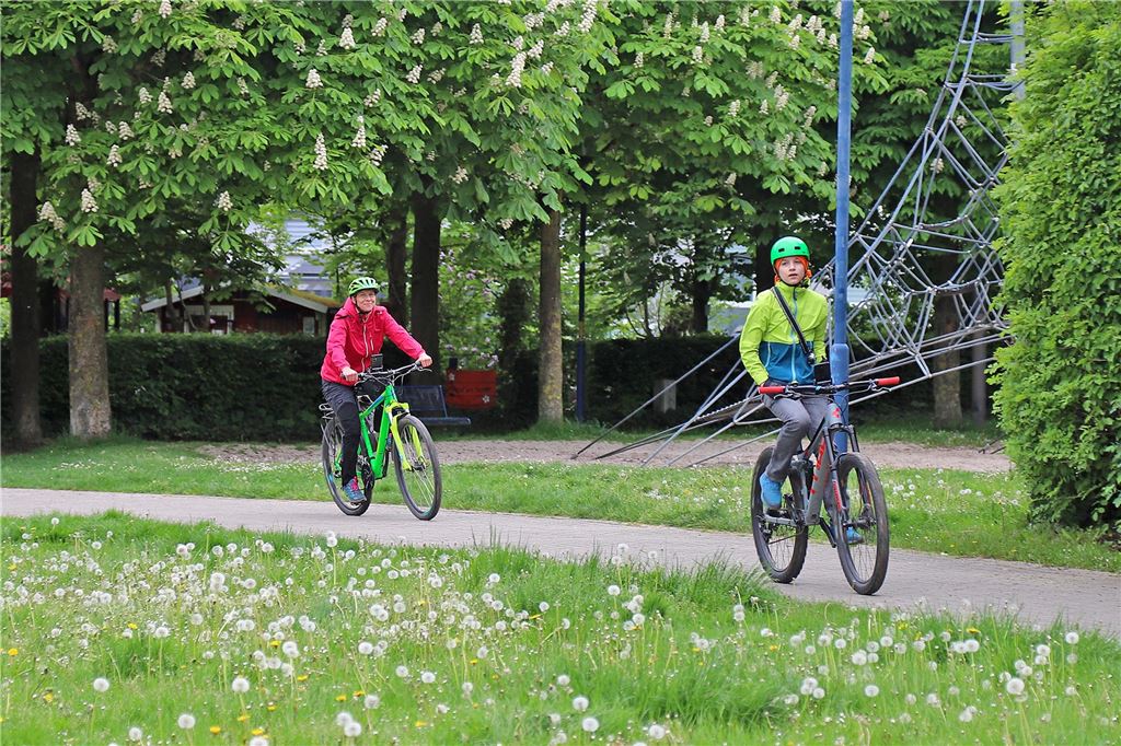 Menschen mit Helm auf einem Fahrrad, die gerade nach ihrer Route am Ziel ankommen.