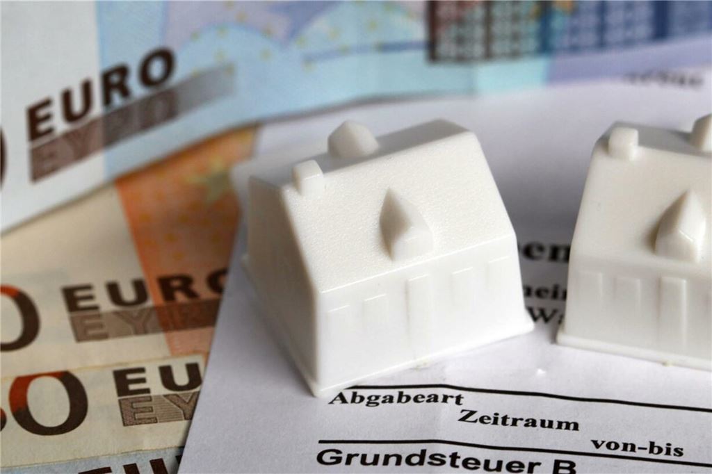 Bergkamen wird den Grundsteuerhebesatz anpassen müssen Spielzeughäuser stehen auf einem Grundsteuerbescheid und Geldscheinen.