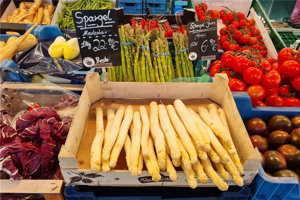 Auf dem Wochenmarkt gibt es schon deutschen Spargel Spargel-Stangen liegen in einer Holzkiste.
