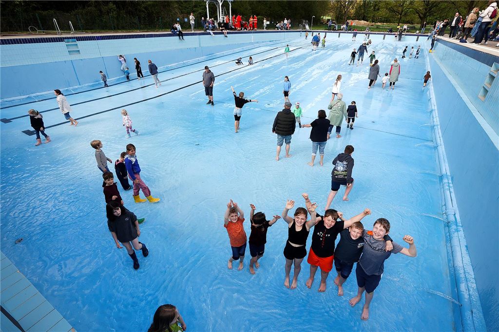 „Wasser marsch“ vor dem Saisonstart: Viele Bürger feiern ihr Freibad Kinder, Jugendliche und Erwachsene stehen im Hauptbecken des Freibads Dellwig, während das Befüllen vor dem Saisonstart beginnt.