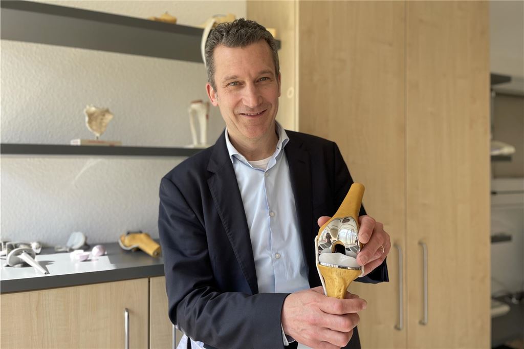 Neuer Chefarzt in Kirchlinde ist Top-Mediziner auf Focus-Bestenliste Professor Dr. Sebastian Seitz steht in einem Behandlungszimmer im Katholischen Krankenhaus Dortmund-West und hält eine Knieprothese in die Kamera.