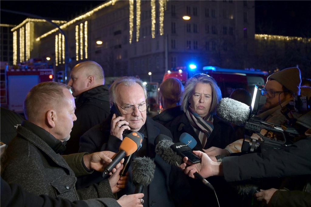 Anschlag auf Magdeburger Weihnachtsmarkt: Fünf Tote, 200 Verletzte - Kanzler Scholz im Livestream Ministerpräsident Reiner Haseloff, umringt von Reportern, viele Mikrofone, im Hintergrund Blaulicht und Einsatzfahrzeuge.