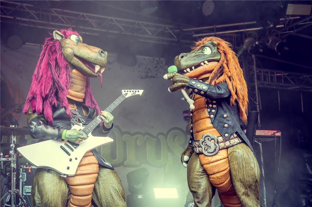 Heavy Metal-Konzert für Kinder: Was „Heavysaurus“ kindgerecht macht Riffi Raffi und Mr. Heavysaurus stehen mit Gitarre und Mikrofon auf der Bühne.