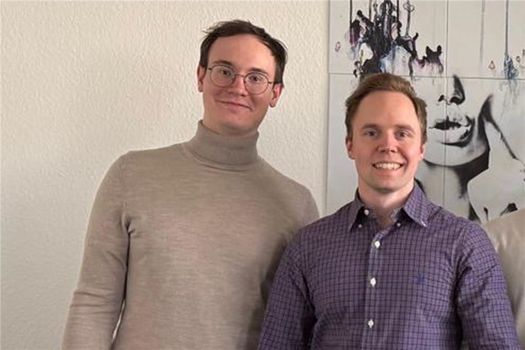 Junger Unternehmer gründet KI-Start-up: Das ist seine Geschäftsidee Zwei junge Männer stehen nebeneinander und lächeln in die Kamera.