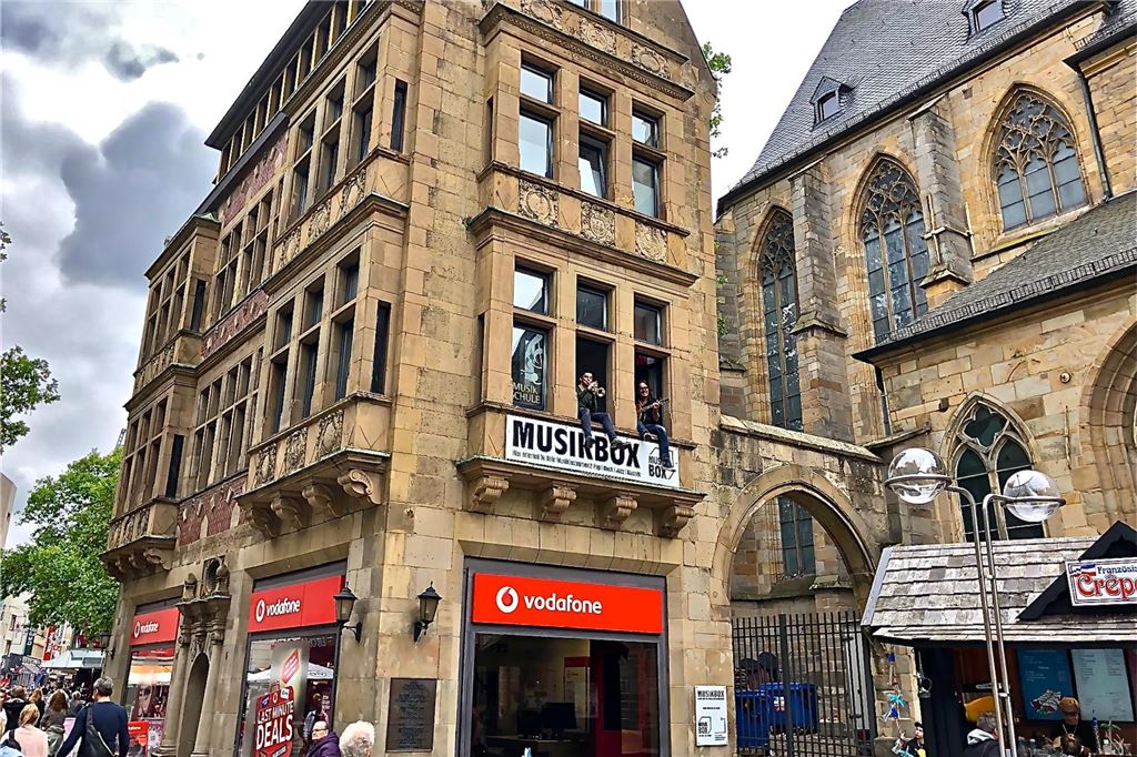 Musikschule Jellinghaus überommen: Mitarbeiter und Geschichte gerettet Schönert mit Gitarre und Staubach mit Trompete im Fenster ihrer Etage im historischen Gebäude der Musikbox.