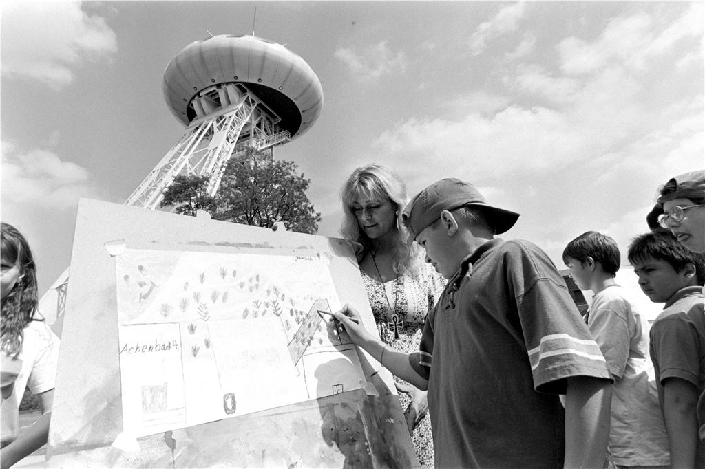 „LünTec“-Ufo feiert 30. Geburtstag: Buntes Programm bei freiem Eintritt Eine Gruppe von Schülern steht vor dem Ufo und bemalt eine Karte.