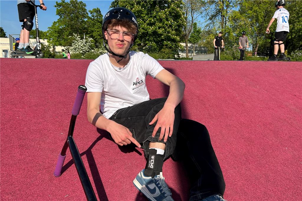 Max Bijak (14) aus Selm fährt professionell Stunt-Scooter Max Bijak sitzt am Skatepark Selm und zeigt auf seine Knöchelschoner.
