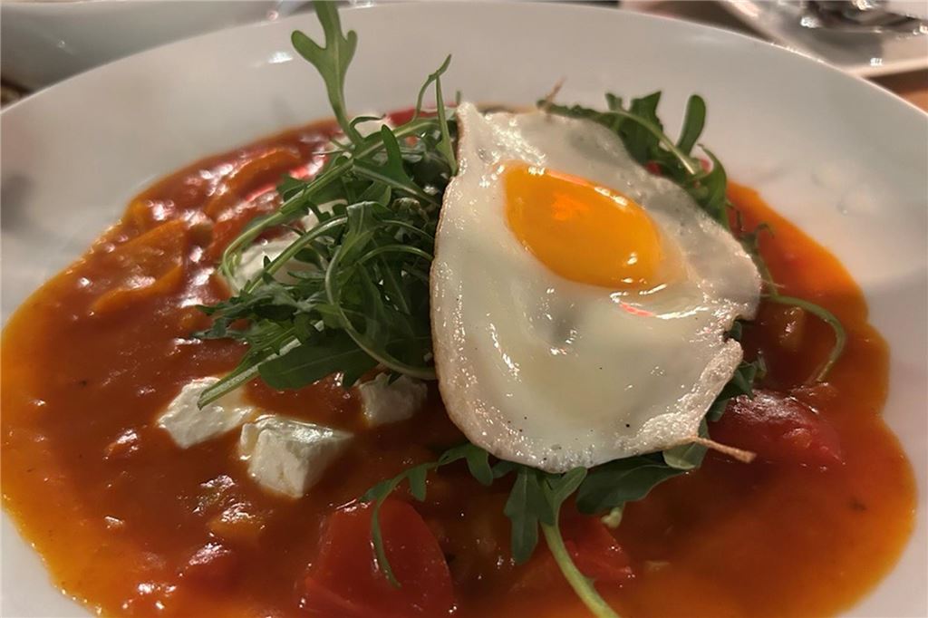 Perfektes Steak und ein Veggie-Experiment im Steakhouse „Le Bon Filet“ Shakshuka auf einem weißen Teller. Darauf liegt Rucola und ein Spiegelei im „Le Bon Filet Steakhouse“ in Dortmund