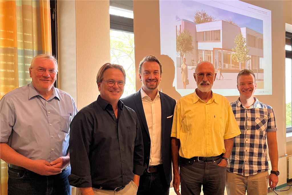 Umbau ab 2025: Kirche öffnet Katharinentreff in die Stadt Rainer Engel (l.) und Ludwig Holzbeck (2. v. r.) vom Kirchenvorstand sowie Architekt Christian Weicken (2. v. l.), Verwaltungsleiter Stefan Spallek (M.) und Gemeindeferent Janfelix Müller bei der Vorstellung der Planungen vor einer Leinwand.