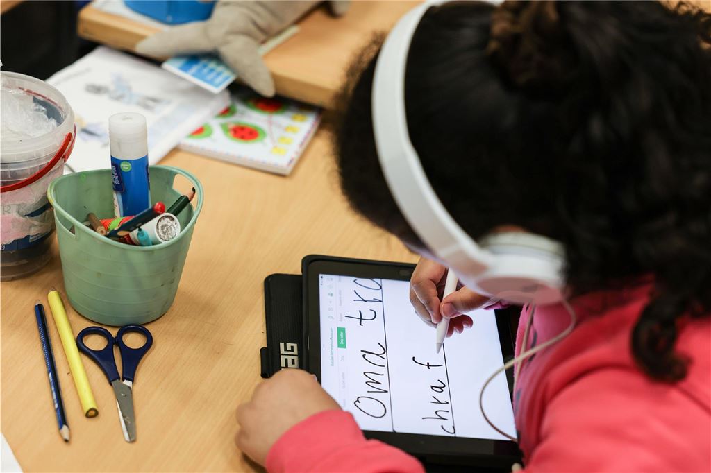 Immer erreichbar sein: Handys an Holzwickeder Grundschulen Eine junge Schülerin schreibt mit einem elektronischen Stift auf den Bildschirm eines Tablets.