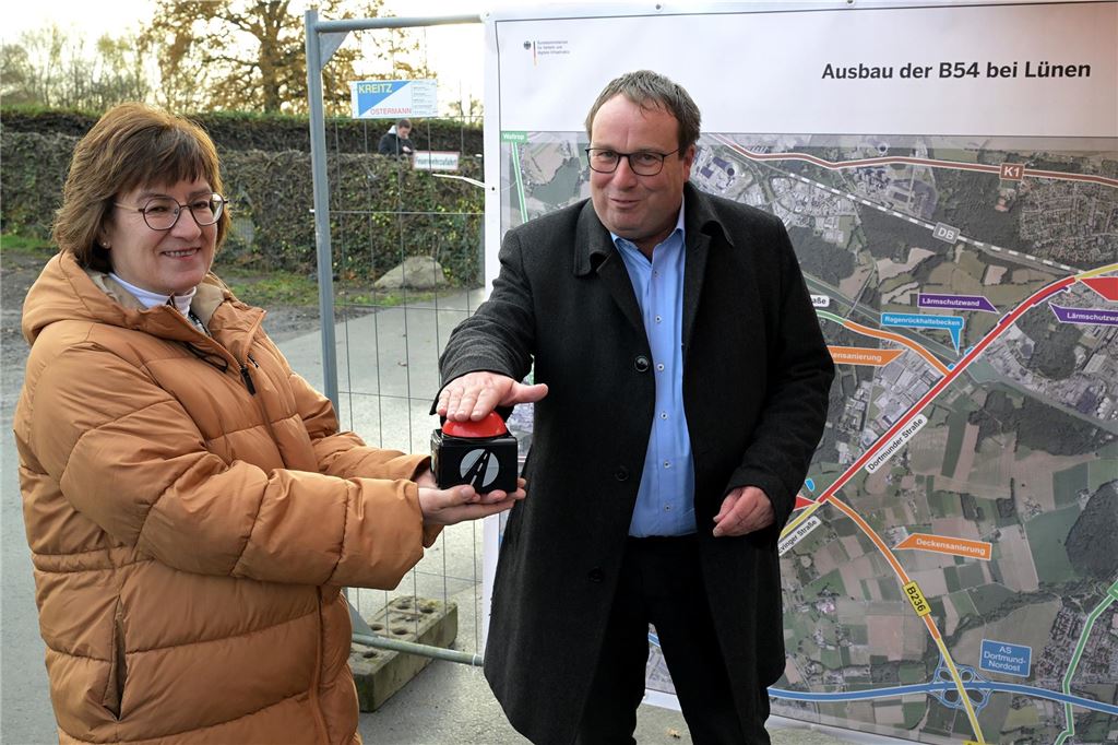 B54-Freigabe: „Als wenn man Verstopfung aus Waschbecken löst“ NRW-Verkehrsminister Oliver Krischer drückt bei der Freigabe der B54 in Lünen auf einen symbolischen Knopf, den Straßen.NRW-Direktorin Dr. Petra Beckefeld in den Händen hält.