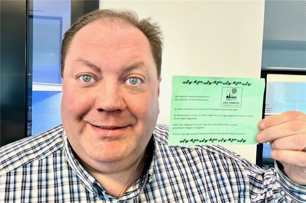 Weihnachtsgruß für Falschparker? „Wäre falsches Signal“ ein Mann hält einen grünen Zettel in der Hand