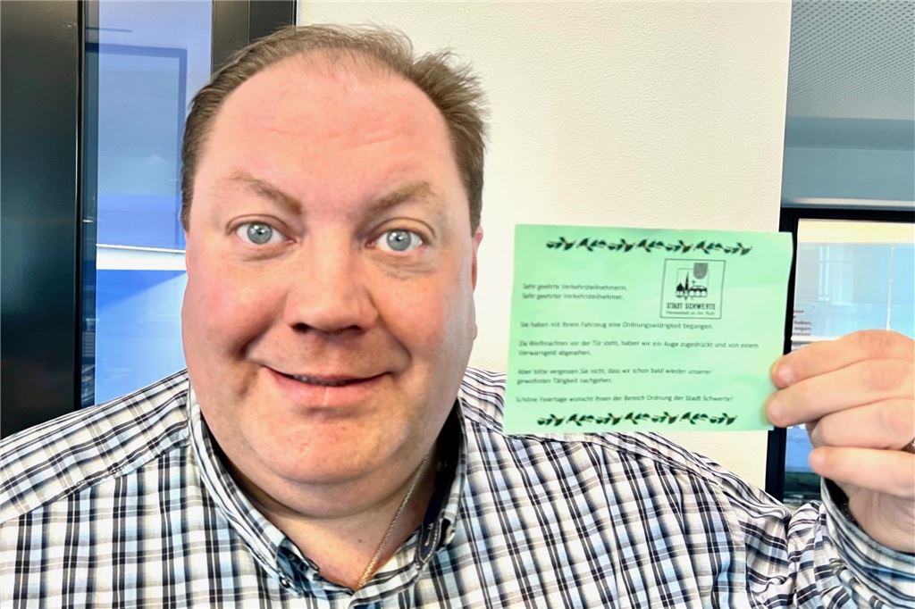 Weihnachtsgruß statt Knöllchen: Stadt überlegt Einführung Ein Mann hält einen grünen Zettel in der Hand