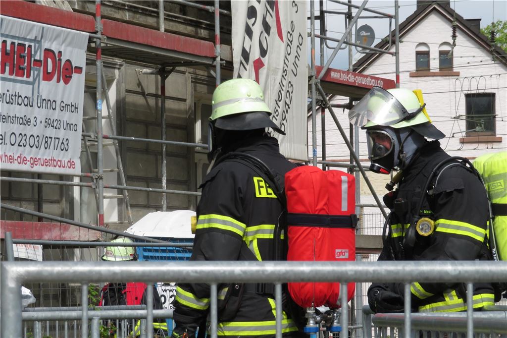 Feuerwehr in der Innenstadt: Brand im Dachstuhl neben Einkaufszentrum Feuerwehrleute tragen Atemschutz.