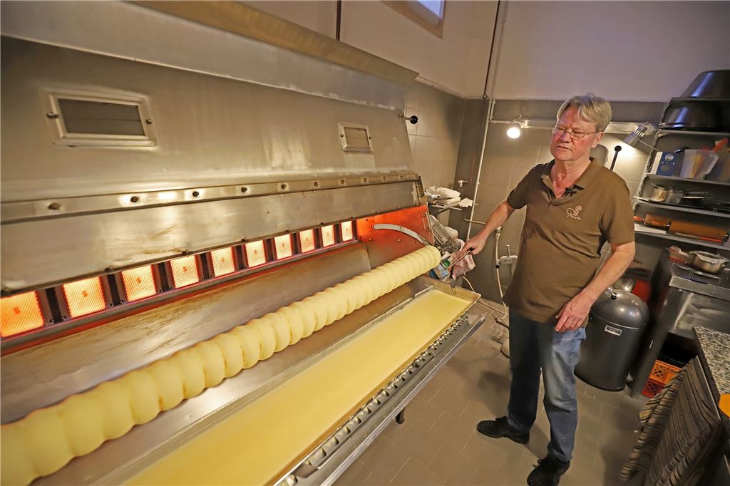 Mit Video: So werden die berühmten Baumkuchen von Prünte hergestellt Uwe Petersmann taucht die Walze in regelmäßigen Abständen in die Masse ein.