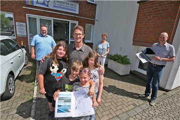 Vater Christian Peterson, hier im Vordergrund mit vier seiner fünf Kinder, freut sich über die Unterstützung durch Spendengelder. Sie erlauben seiner Familie ein fünftätigen Zelturlaub ab der Möhne. Die Aktion Umfairteilen ist ein großer Erfolg, wissen Ludger Büngener (Dekanat Unna, links), Silvia Engemann (Caritas, hinten) und Michael Arndsmeier (Schwerter Netz, rechts).