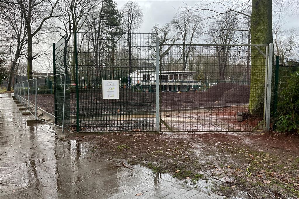 Umbau auf dem Tennisplatz: Lkw hinterlassen Spuren im Kurpark Der Blick durch einen Zaun auf eine Baustelle. Dahinter liegt eine Gaststätte.